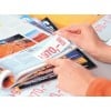 A close-up of a person's hand flipping through a colorful magazine, showcasing an image of a red landscape and a price tag marked €970.