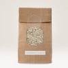 The image shows a brown paper bag with a circular window displaying white rice inside. The bag is labeled 'UNVERPACKT-LADEN.'