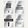 Das Bild zeigt vier Schilder mit unterschiedlichen Texten und Symbolen: einen QR-Code mit 'ABNAHMESTATION 1', 'TESTCENTER', 'DESIGN COMPANY EMPFANG' mit einem Pfeil nach oben und 'BERUFLICHE SCHULE' mit einem Symbol und 'Elektrisches Betriebsmittel Nr. 004'.
