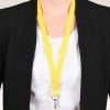 Das Bild zeigt eine Person, die einen schwarzen Blazer über einem weißen Hemd trägt, mit einem leuchtend gelben Schlüsselband, das von ihrem Hals hängt und an dem ein Clip befestigt ist.