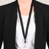 Das Bild zeigt eine Person, die einen schwarzen Blazer über einem weißen Hemd trägt, mit einem Schlüsselband um den Hals.