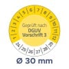Das Bild zeigt ein gelbes, rundes Messgerät mit der Aufschrift „Geprüft nach DGUV Vorschrift 3“ und Zahlen am Rand, die Dimensionen anzeigen, sowie eine Messung von „Ø 30 mm“ am unteren Rand.