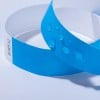 Das Bild zeigt zwei blaue Identifikationsarmbänder, wobei eines das andere überlappt, mit Wassertropfen auf ihrer Oberfläche. Sie scheinen aus einem papierähnlichen Material zu bestehen und haben auf einer Seite einen Aufkleber mit Nummern.