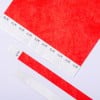 Das Bild zeigt ein großes rotes Blatt Papier mit Klebestreifen, die oben angeordnet sind, sowie ein paar zusätzliche Streifen unten, alle mit Zickzackmustern.