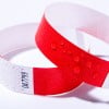 Das Bild zeigt zwei Armbänder, eines in Rot und das andere in einem Mix aus Rot und Weiß mit einem Zickzackmuster. Das rote Armband hat Wassertropfen auf seiner Oberfläche.