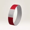 Das Bild zeigt ein rotes Armband. Das Armband hat einen weißen Abschnitt mit Zickzackmustern und eine darauf angezeigte Nummer, die möglicherweise eine Identifikationsnummer darstellt.