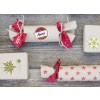 Das Bild zeigt mehrere dekorierte Geschenkpakete, die auf einer Holzfläche angeordnet sind. Die Geschenke sind in Packpapier mit festlichen Bändern und Aufklebern verpackt und vermitteln ein gemütliches, festliches Thema.